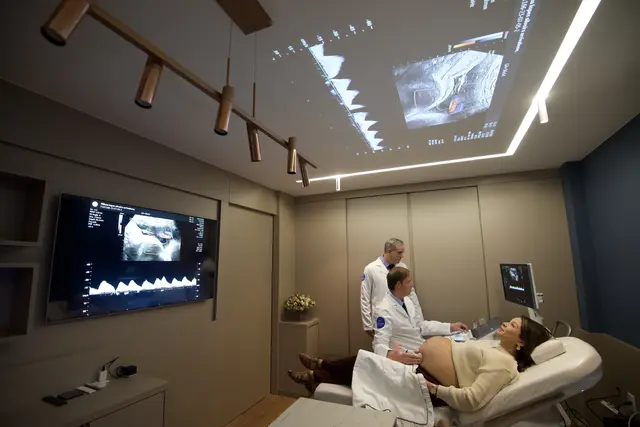 Exame de ultrassom com Doppler, a gestante na maca e os dois médicos